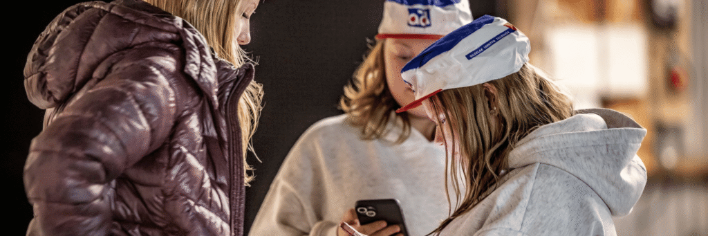 Tre personer som står runt en telefon